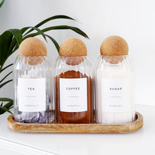 Load image into Gallery viewer, Three glass bottles labeled 'Tea', 'Coffee', and 'Sugar' on a wooden tray with a plant in the background.