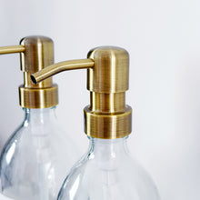 Load image into Gallery viewer, Set Of 2 Clear Bottles - Glass Or Plastic - Hands & Dishes - Brushed Light Gold Metal Pumps