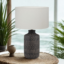 Load image into Gallery viewer, Black and natural textured stoneware lamp base with white linen shade, inspired by Bali and mediterranean interiors.