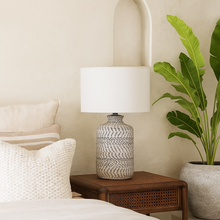 Load image into Gallery viewer, Boho table lamp with neutral stoneware base and white linen fabric shade in a mediterranean inspired room.