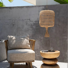 Load image into Gallery viewer, The Dumpling boho style rattan pendant light shade hanging in a mediterranean courtyard. Perfect for a minimalist aesthetic.