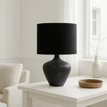 Load image into Gallery viewer, Black ribbed wooden table lamp base with black linen shade on a white table in a minimalist interior.