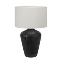 Load image into Gallery viewer, Taika black ribbed wood table lamp base with a white linen fabric drum lamp shade. Ideal for a Mediterranean inspired home interior.