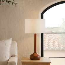 Load image into Gallery viewer, Toma oiled dark wood table lamp base with a white linen shade on a side table in a mediterranean home.