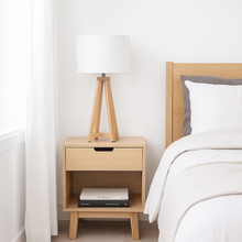 Load image into Gallery viewer, Whitby natural tapered table lamp base with a white linen shade on a bedside table. Perfect for any minimalist Scandi interiors.