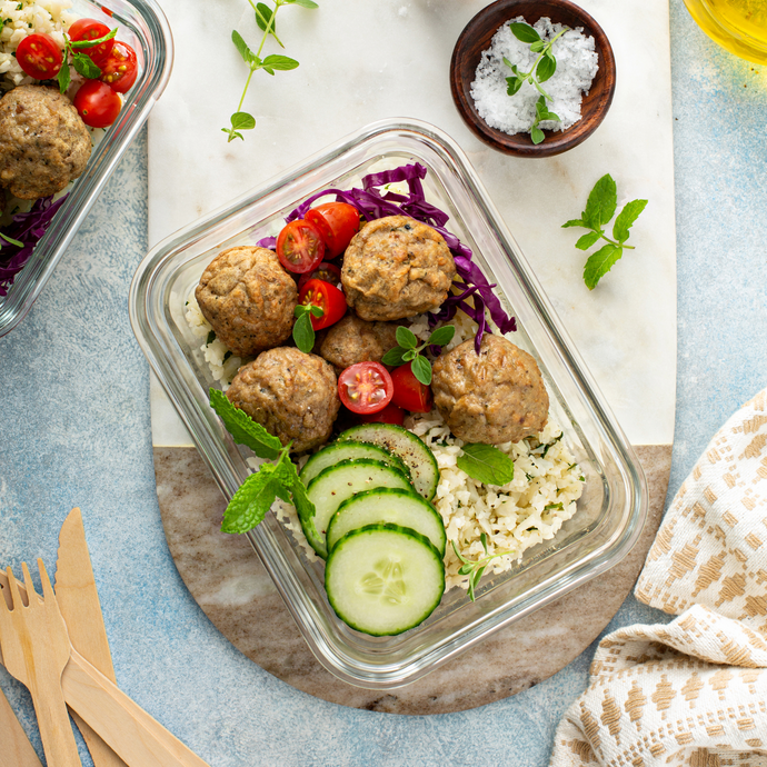Clear rectangle glass food storage container with secure airtight clip lid, displayed on a table, on a chopping board with a prepared meal of meatballs, rice and salad. Ideal for meal prep, kitchen organisation and minimalistic homeware.