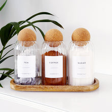 Load image into Gallery viewer, Three glass bottles labeled 'Tea', 'Coffee', and 'Sugar' with cork lids on a wooden tray.

