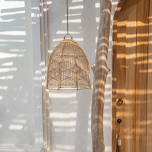 Load image into Gallery viewer, The Bala boho style rattan light shade hanging in a sunny outdoor courtyard
