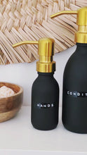 Load and play video in Gallery viewer, Matt Black Glass Dispenser Bottle With Stamped Personalised Label &amp; Gold Metal Pump
