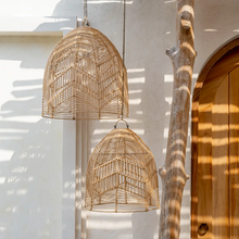 Load image into Gallery viewer, An image of two Bala mediterranean style woven rattan light shades hanging in a sunny outdoor dining area
