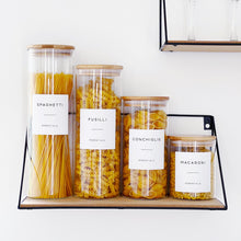 Load image into Gallery viewer, Four clear glass food storage jars on a shelf, on a wall.
The jars have wooden bamboo lids with airtight seals. The are 4 different sizes, 800ml, 1.4L, 1.8L and 2L. Each one has a different pasta in. On the front of each is a white waterproof minimalist personalised printed label.
